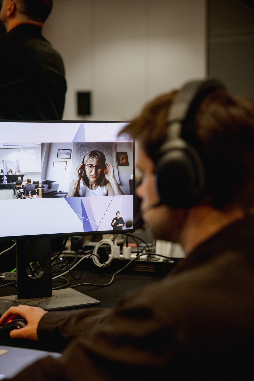 Realizator w słuchawkach przy monitorze z gościem zdalnym