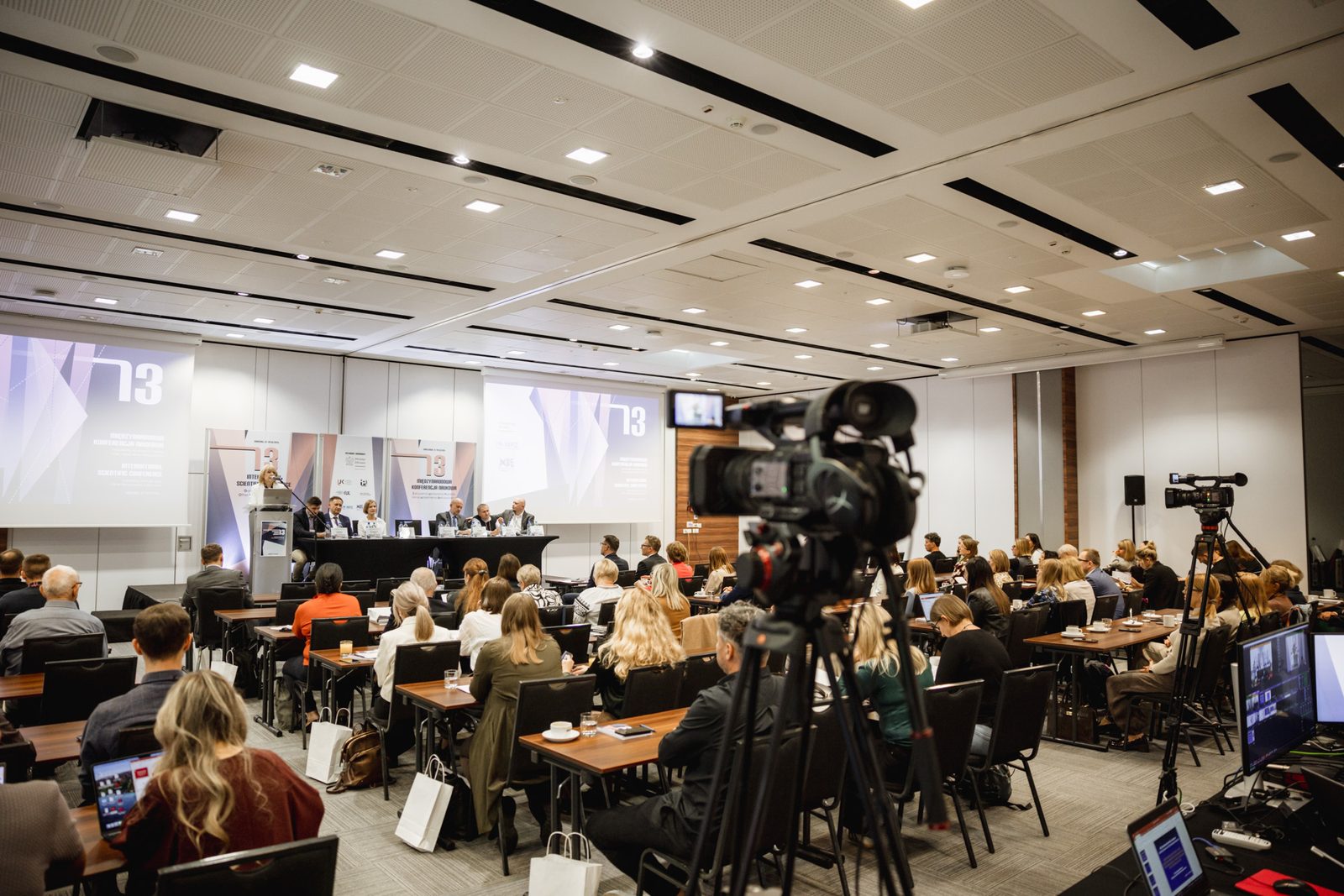 Sala konferencyjna z kamerą na statywie podczas wystąpienia