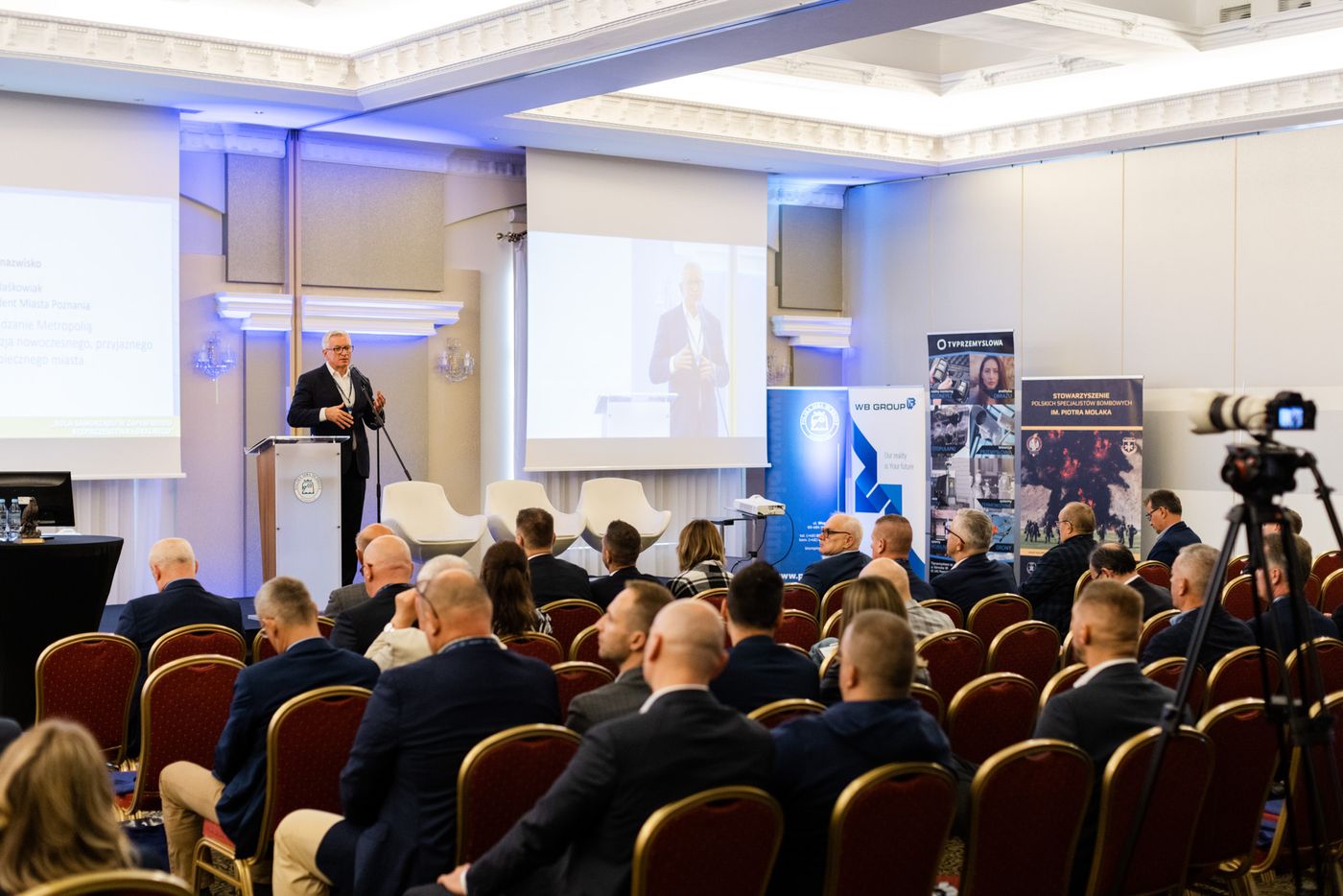 Sala konferencyjna podczas wystąpienia, kamera na statywie